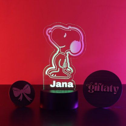 A personalized 3D acrylic LED night light featuring the character Snoopy in a sitting pose, illuminated with a multicolor gradient. The name 'Jana' is printed on the base.